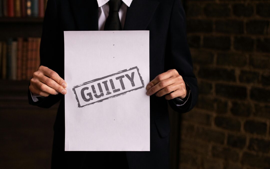 An image of a man in suit holding a sign that says "Guilty.